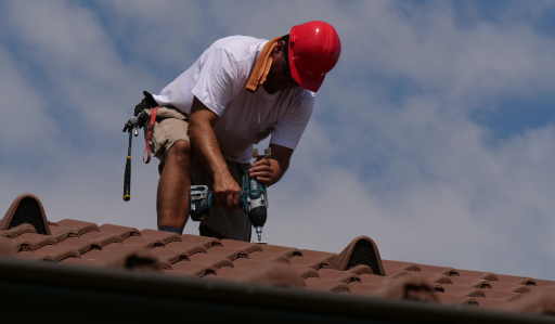 Tetőfedő szakember a tetőn BMI Bramac tetőcserepet rögzít